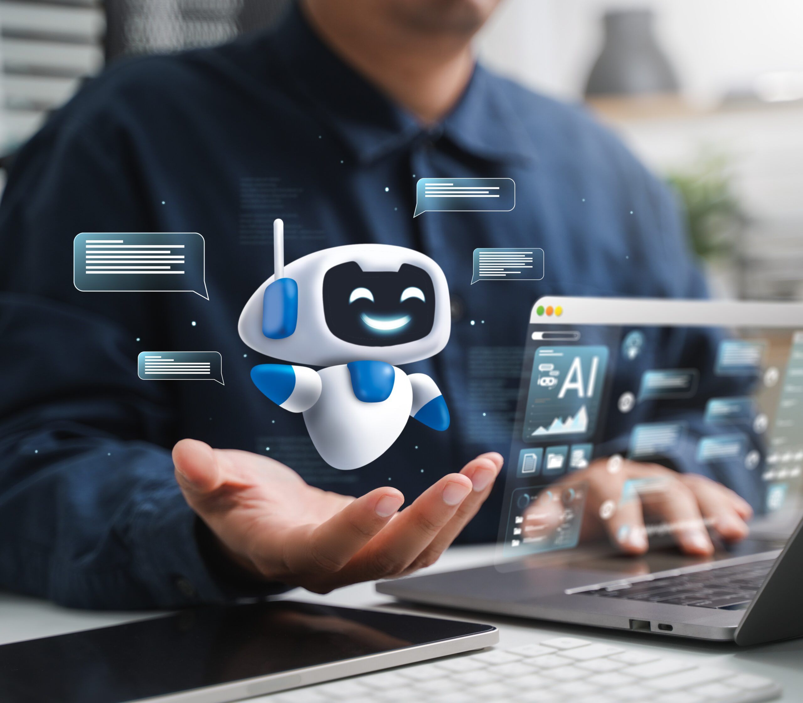 Ein Mann sitzt vor seinem Laptop und hält einen roboterähnlichen KI-Avatar auf seiner Hand.