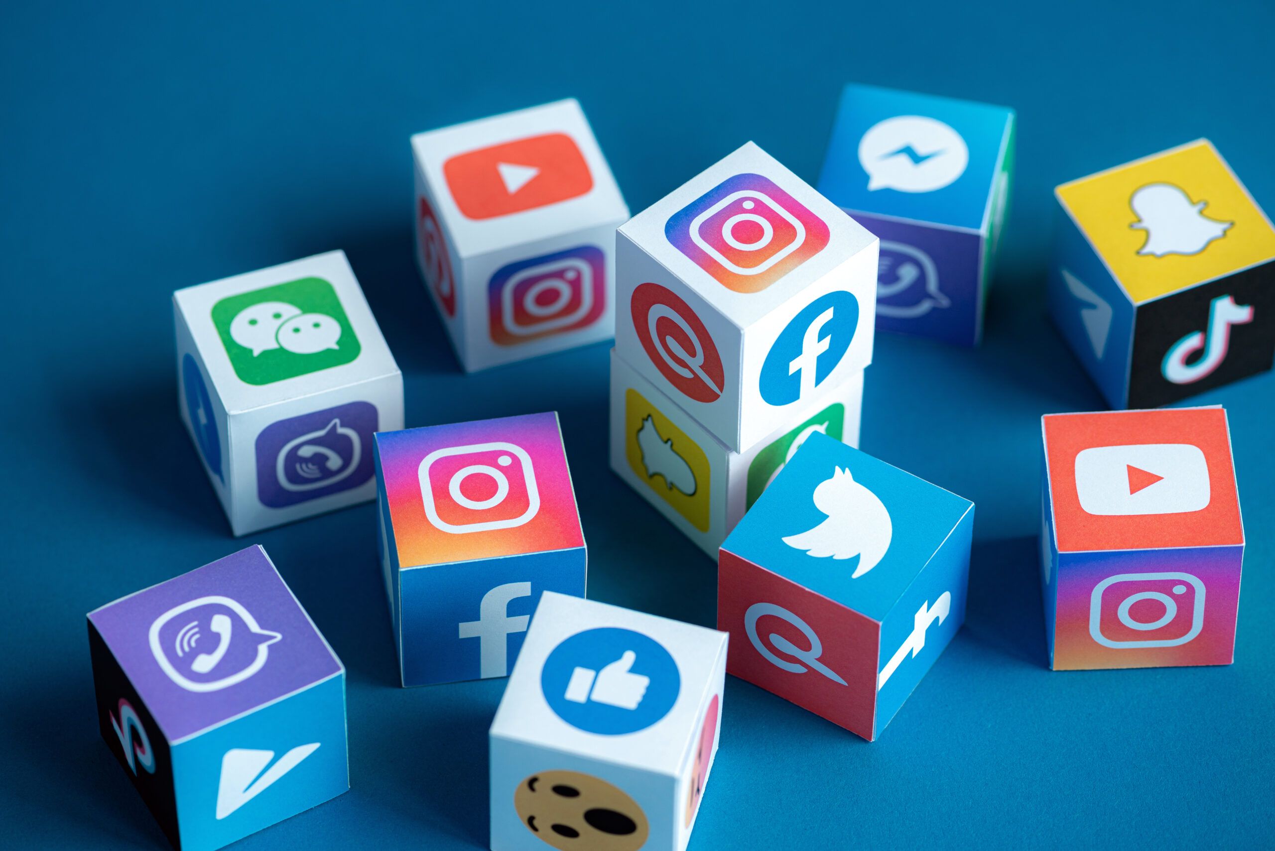 Mehrere Würfel mit Social Media Logos liegen auf einem blauen Tisch.