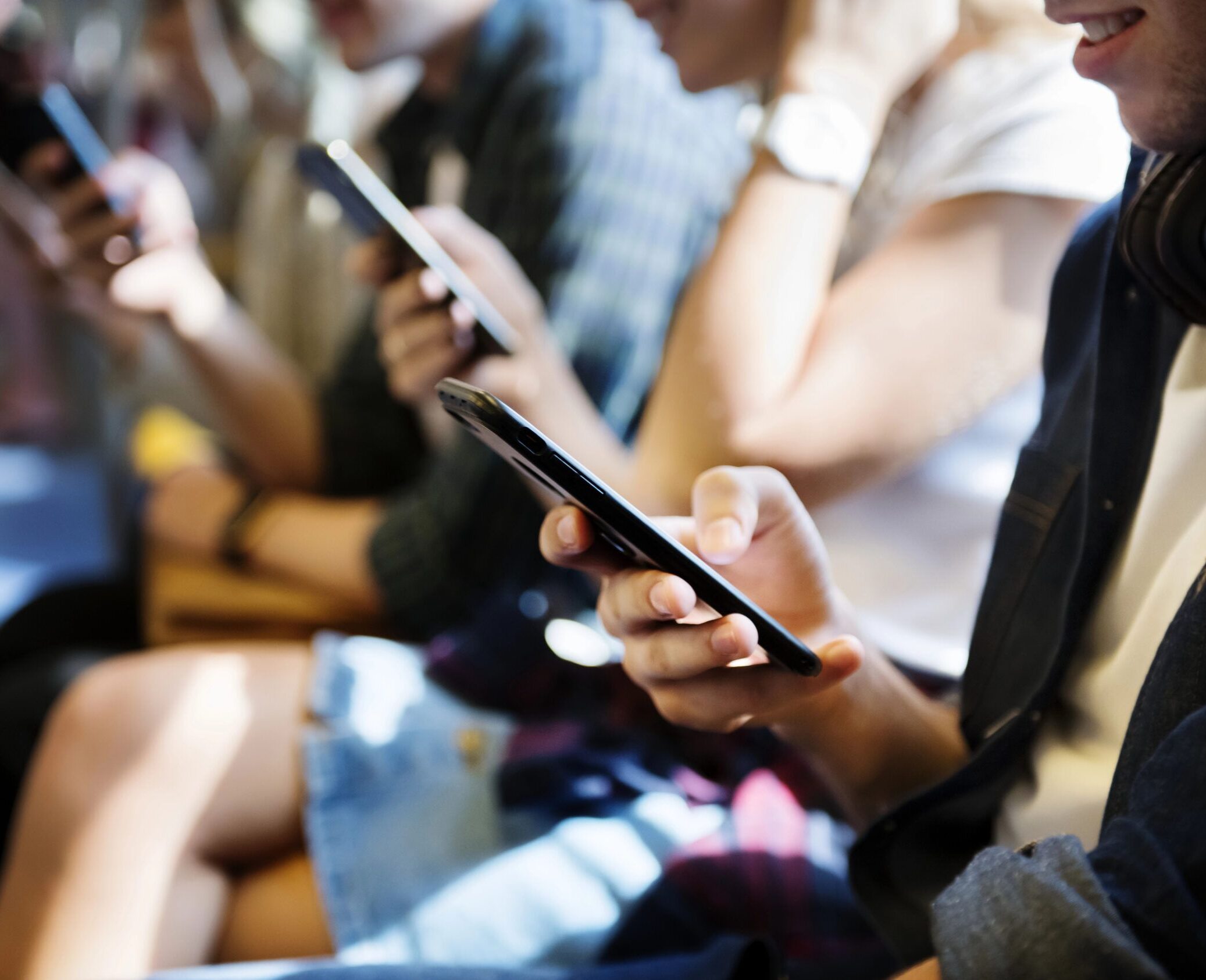 Gruppe junger Erwachsener mit Smartphones in der U-Bahn.